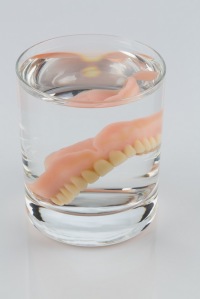 dentures in a water glass, symbolic photo for dentures and care